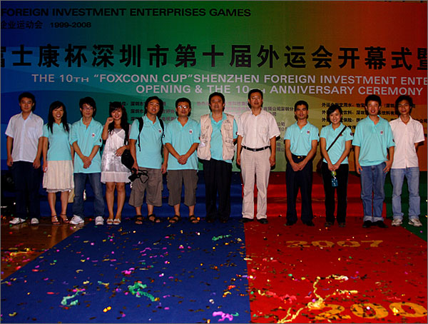 深圳市黑眼睛廣告有限公司參與外運會會務工作的部分員工和文總、徐總在開幕式背景版前留影